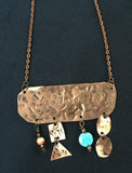 Copper rectangle that has 4 dangle beading and copper geometric patterns hanging from the piece