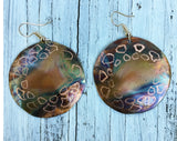 Round copper flame painted earring that measures 1 1/6th with geometric etching around the piece