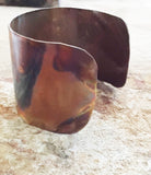 1 1/4th inch wide cuff with lines in a circle of dashes surrounding the flame painted piece