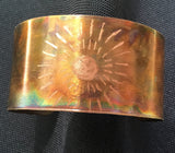 1 1/4th inch wide cuff with lines in a circle of dashes surrounding the flame painted piece